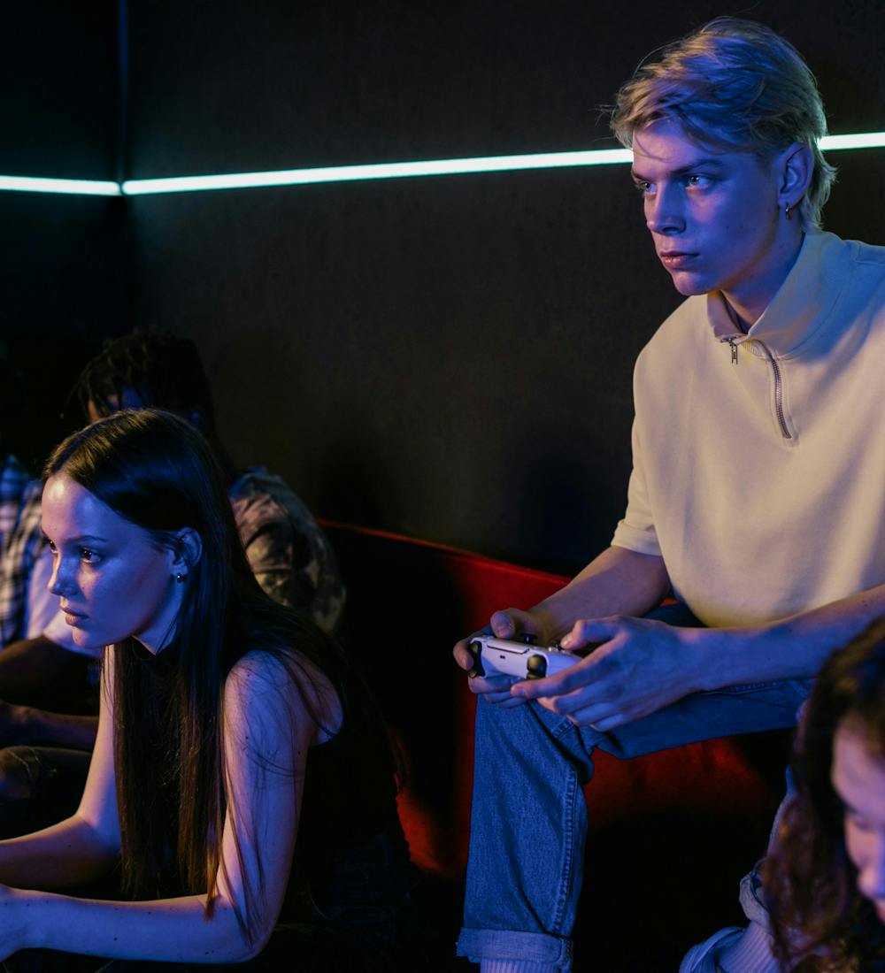 A man in a white polo shirt is sitting next to a woman in a black shirt who is playing a console game