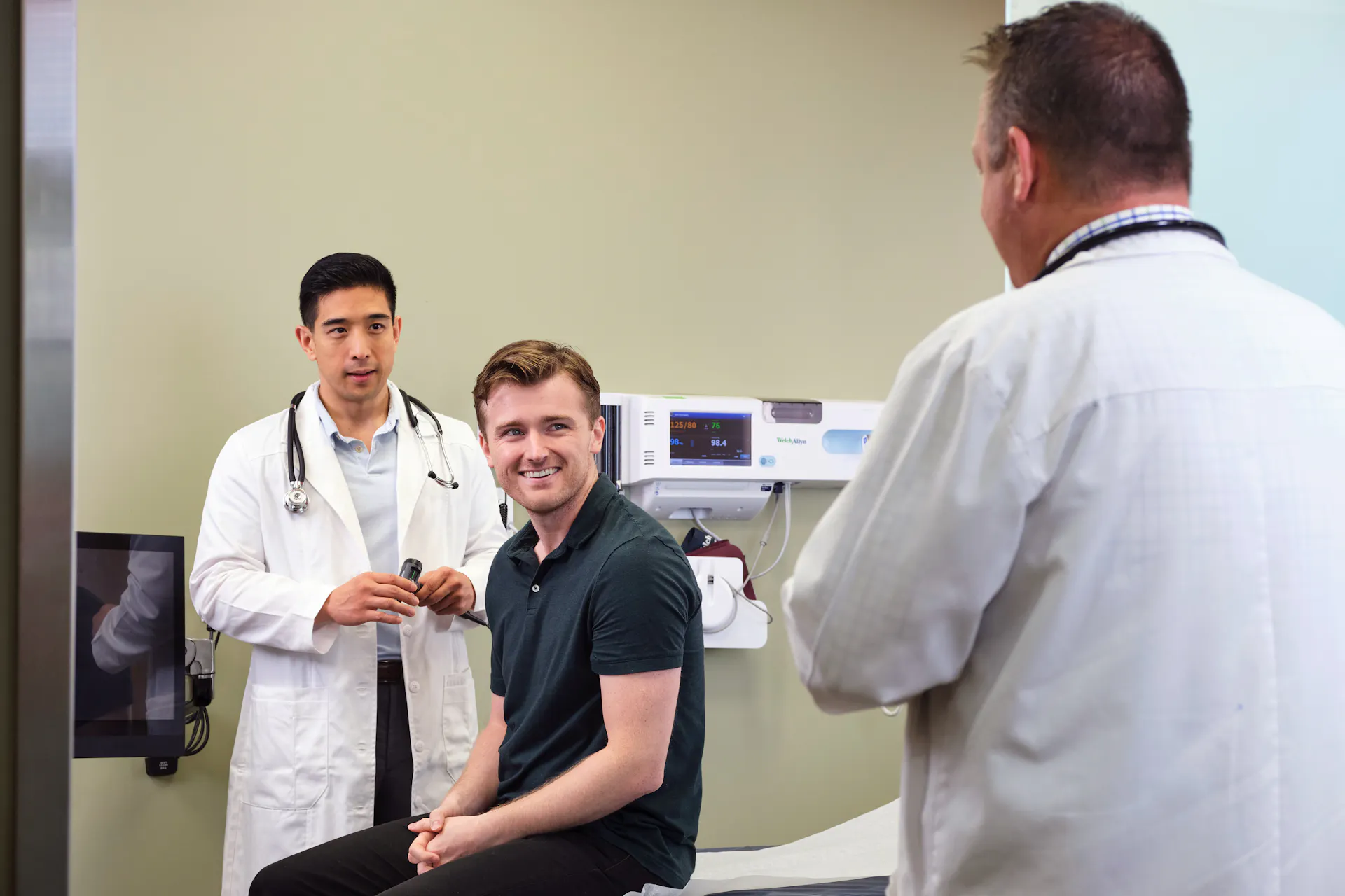 Two providers speaking to a smiling young man