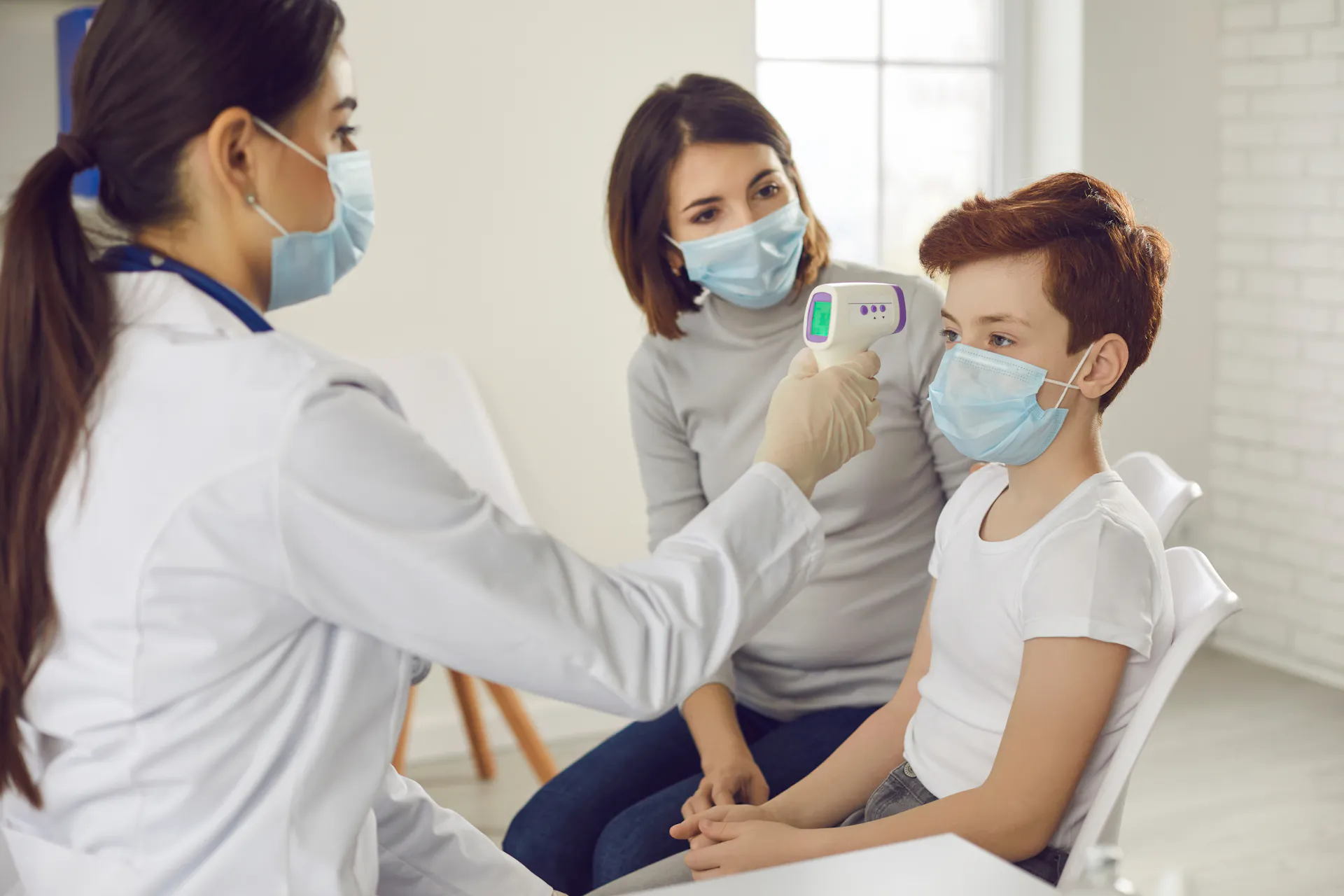 A provider takes the temperature of a young boy