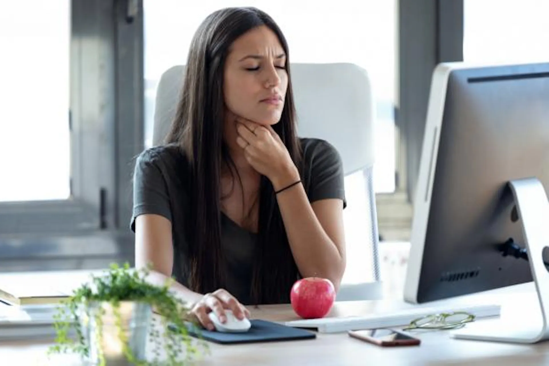 An uncomfortable woman at work feeling her throat