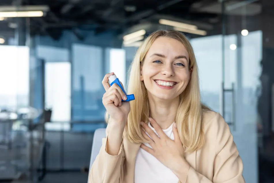 Image of a smiling young woman in a holding an asthma inhaler.