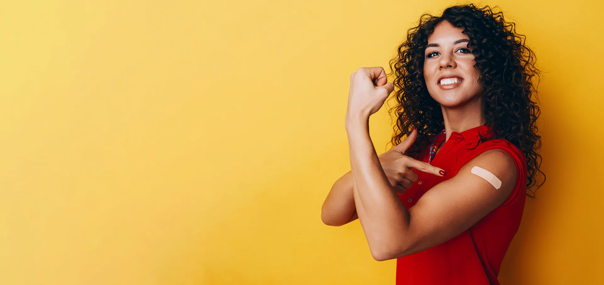 Confident woman pointing to a band-aid on her arm