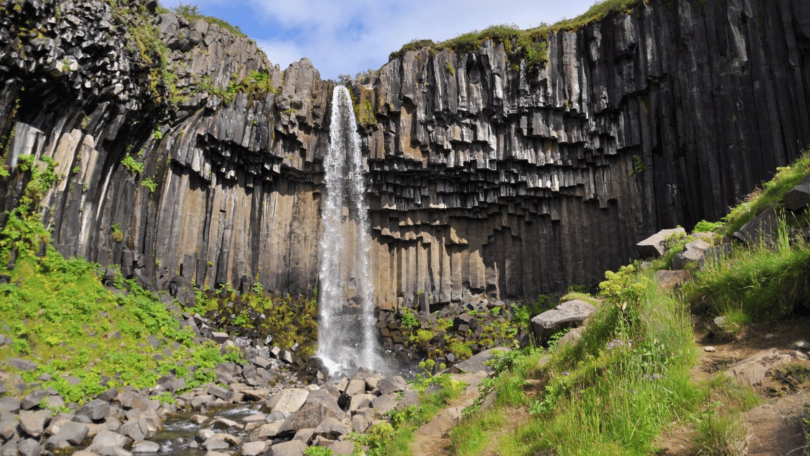 Small waterfall with hexagonal rock columns in Iceland.