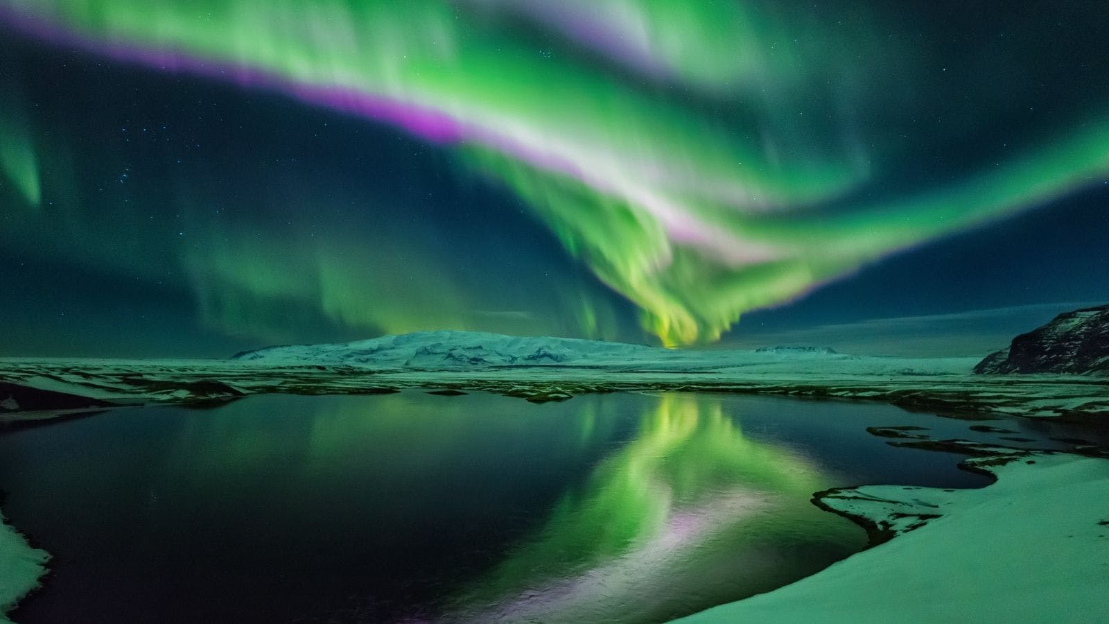 Northern Lights over a body of water in Iceland during winter.