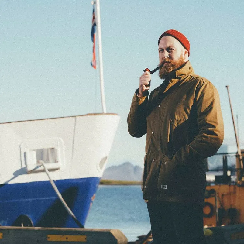 Fisherman stood on the harbor smoking a pipe