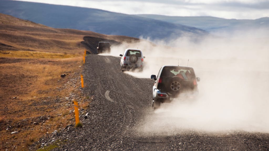 Cars along a gravel track in Iceland kicking up lots of dust.