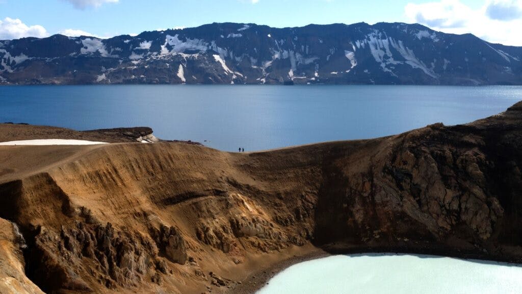 Two hikers on the rim of Lake Víti near the Askja volcanic crater in Iceland.