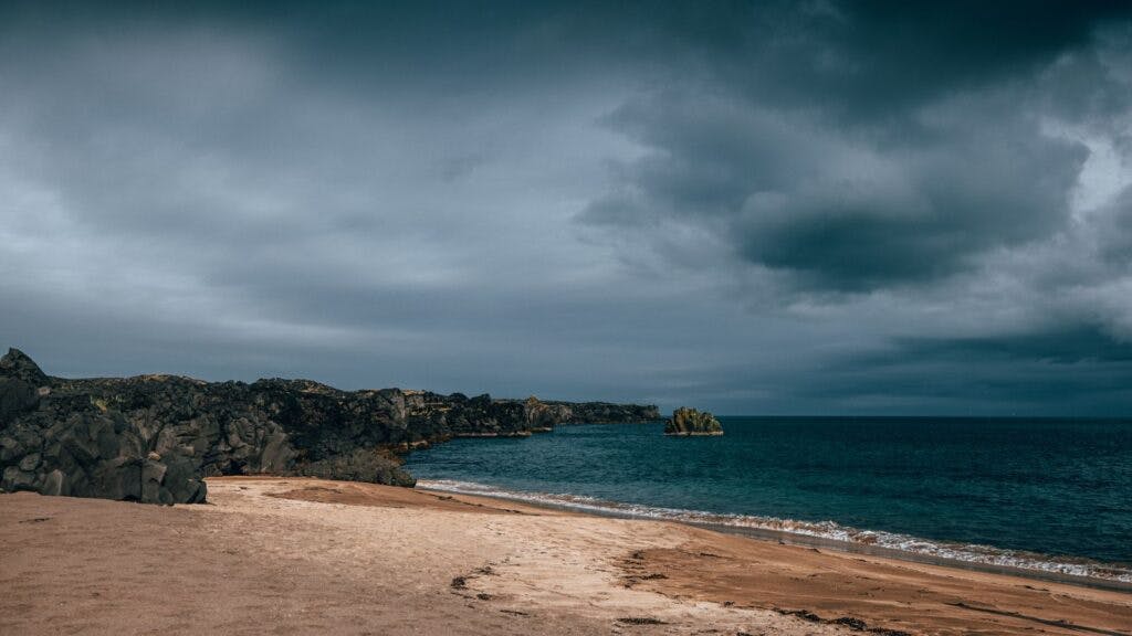 Sandy shores against black cliffs at Skarðsvík, Iceland.
