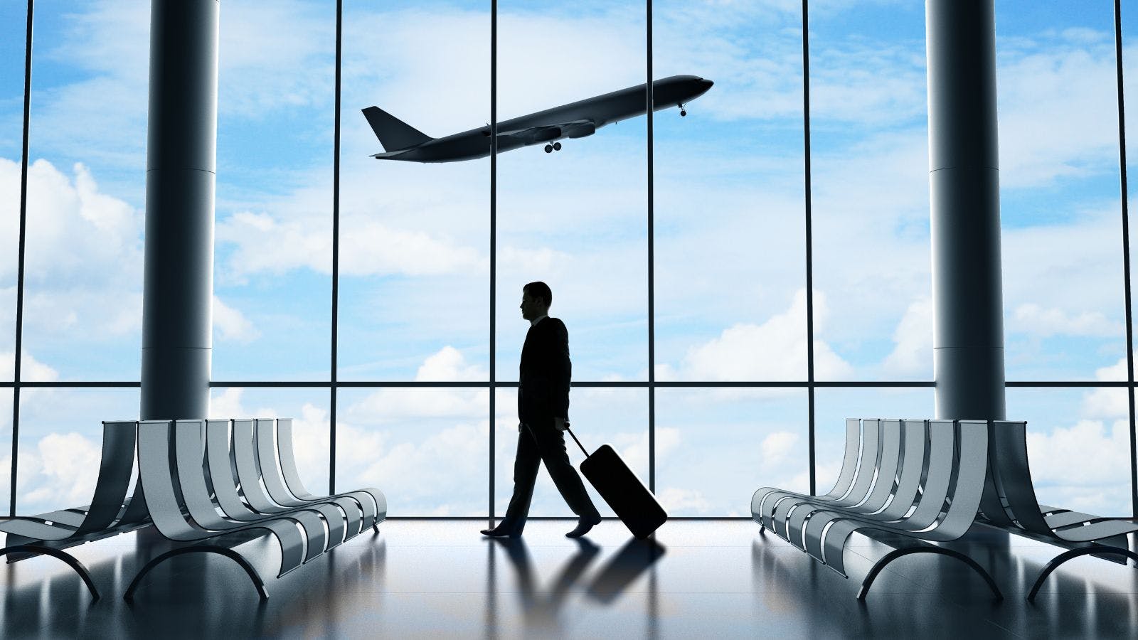 A traveler in an airport with an airplane taking off in the background