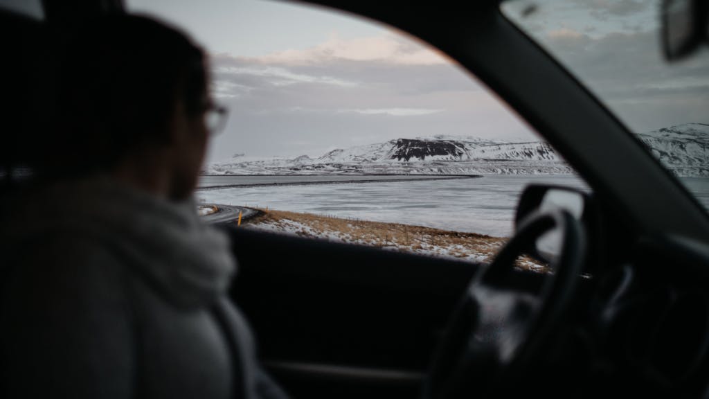 Woman looking out of a car window at an icy landscape in Iceland.