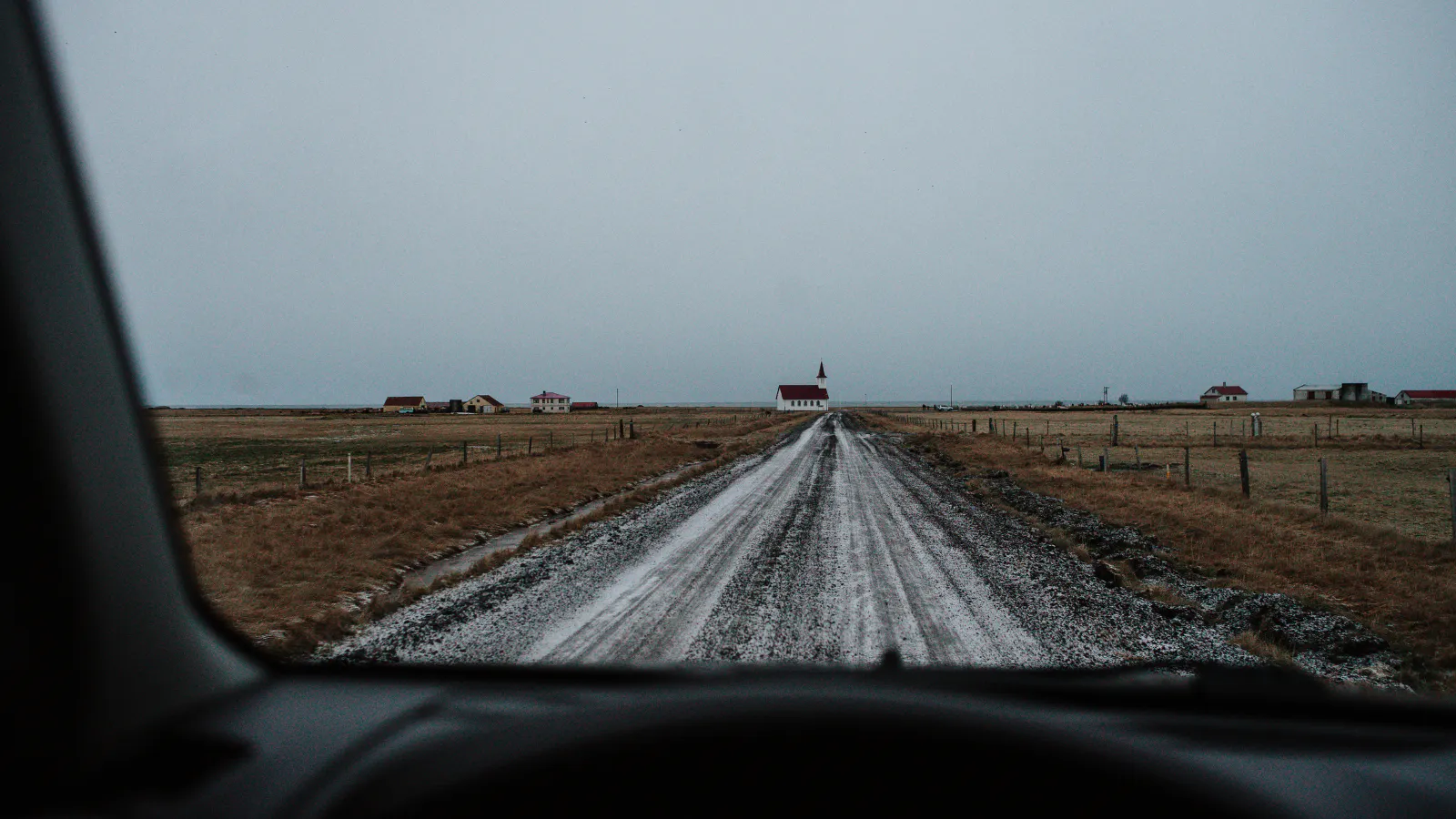View from a car window to a red-roofed church in Iceland.
