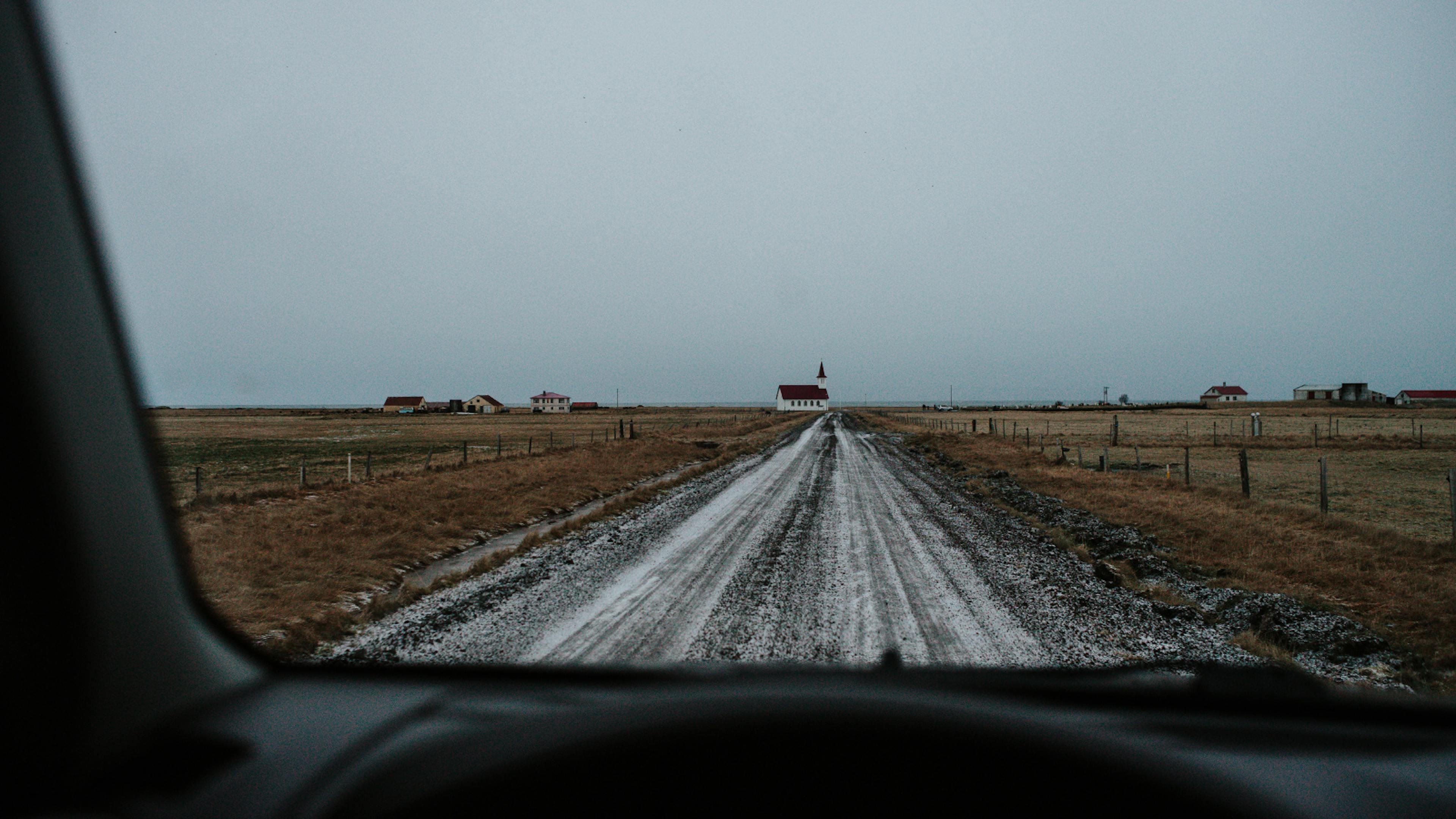 View from a car window to a red-roofed church in Iceland.