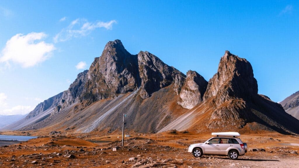 A car against the backdrop of rocky mountains in Iceland.