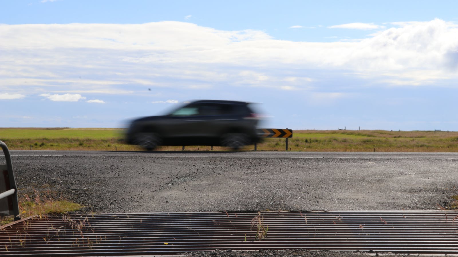 Car driving quickly past a cattle grid in Iceland.