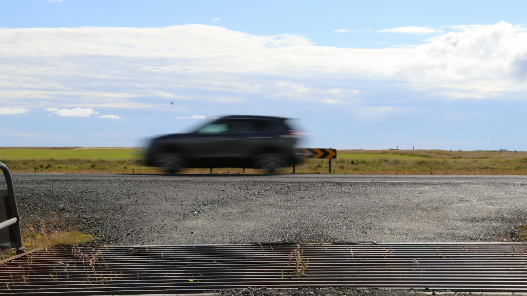 Car driving quickly past a cattle grid in Iceland.