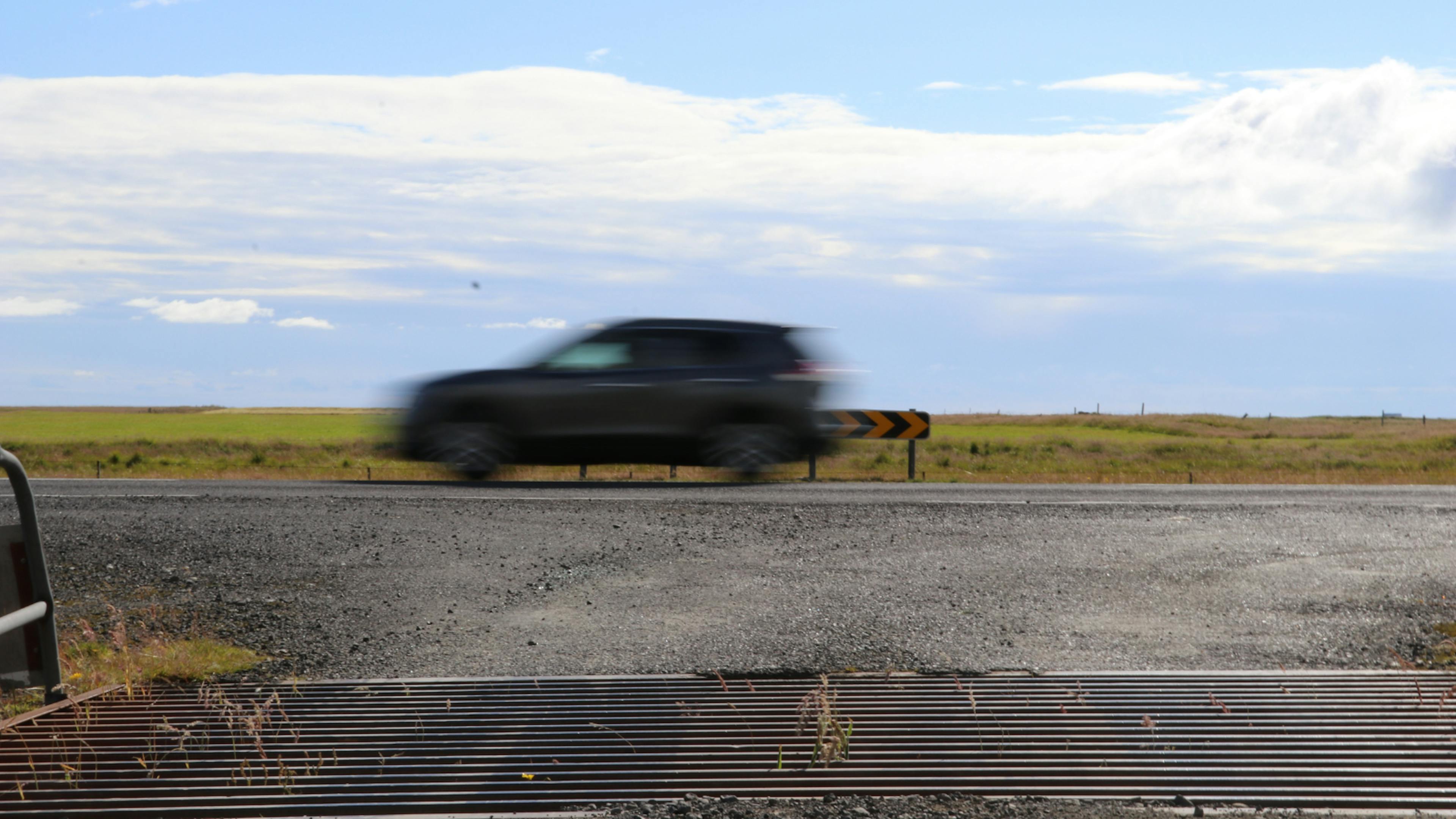Car driving quickly past a cattle grid in Iceland.