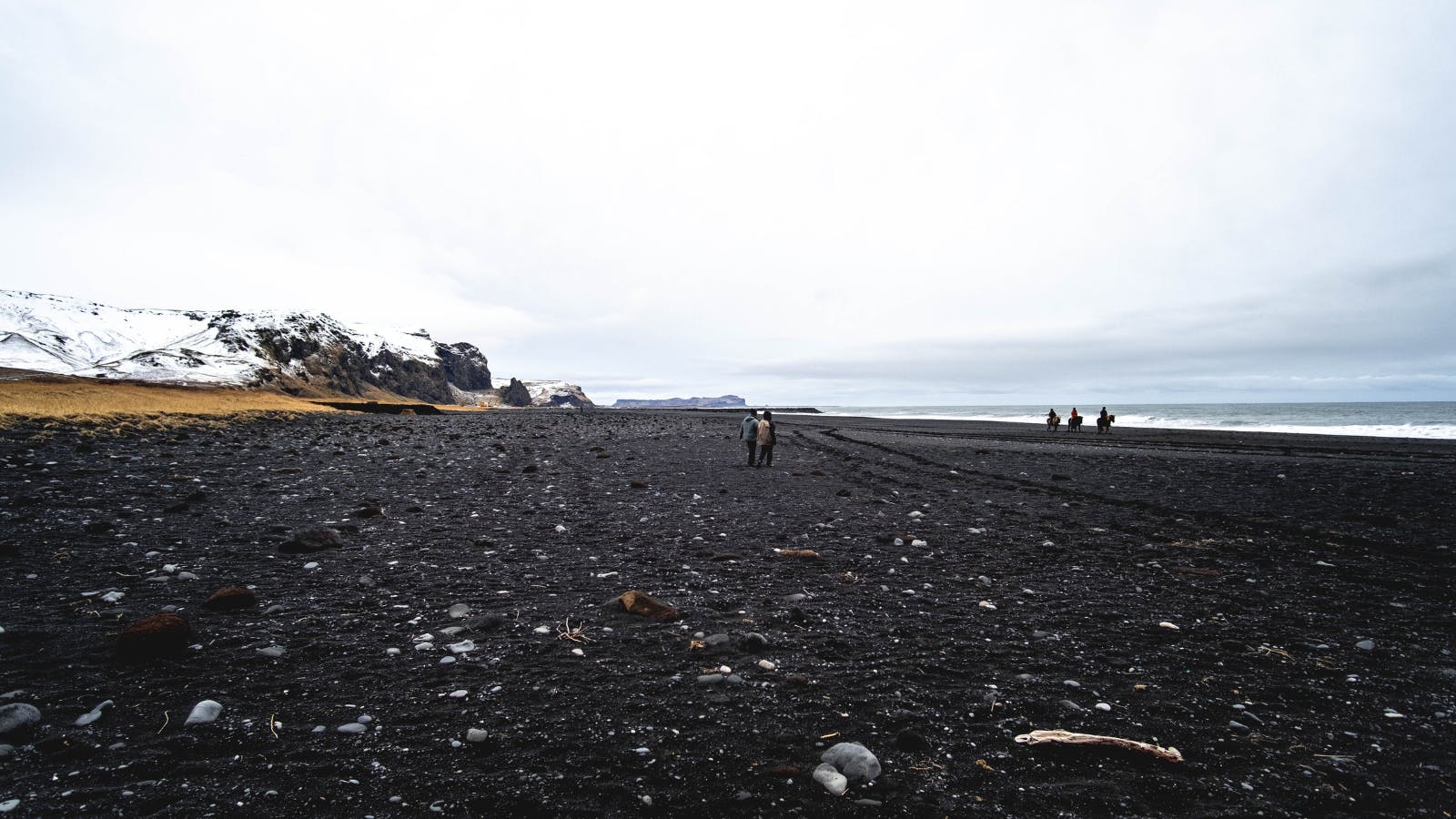 Black sand beach in Iceland with people walking.