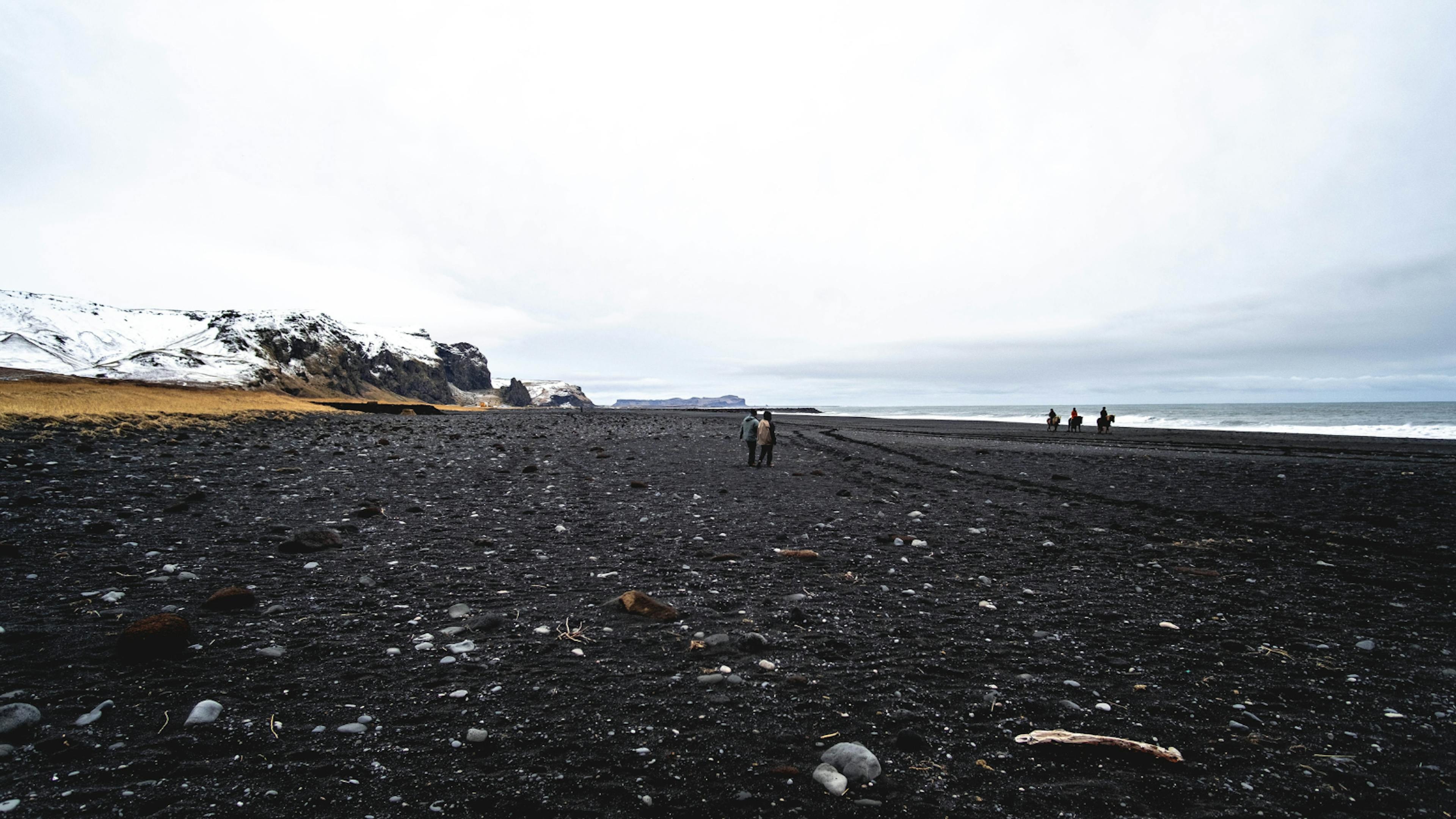 Black sand beach in Iceland with people walking.