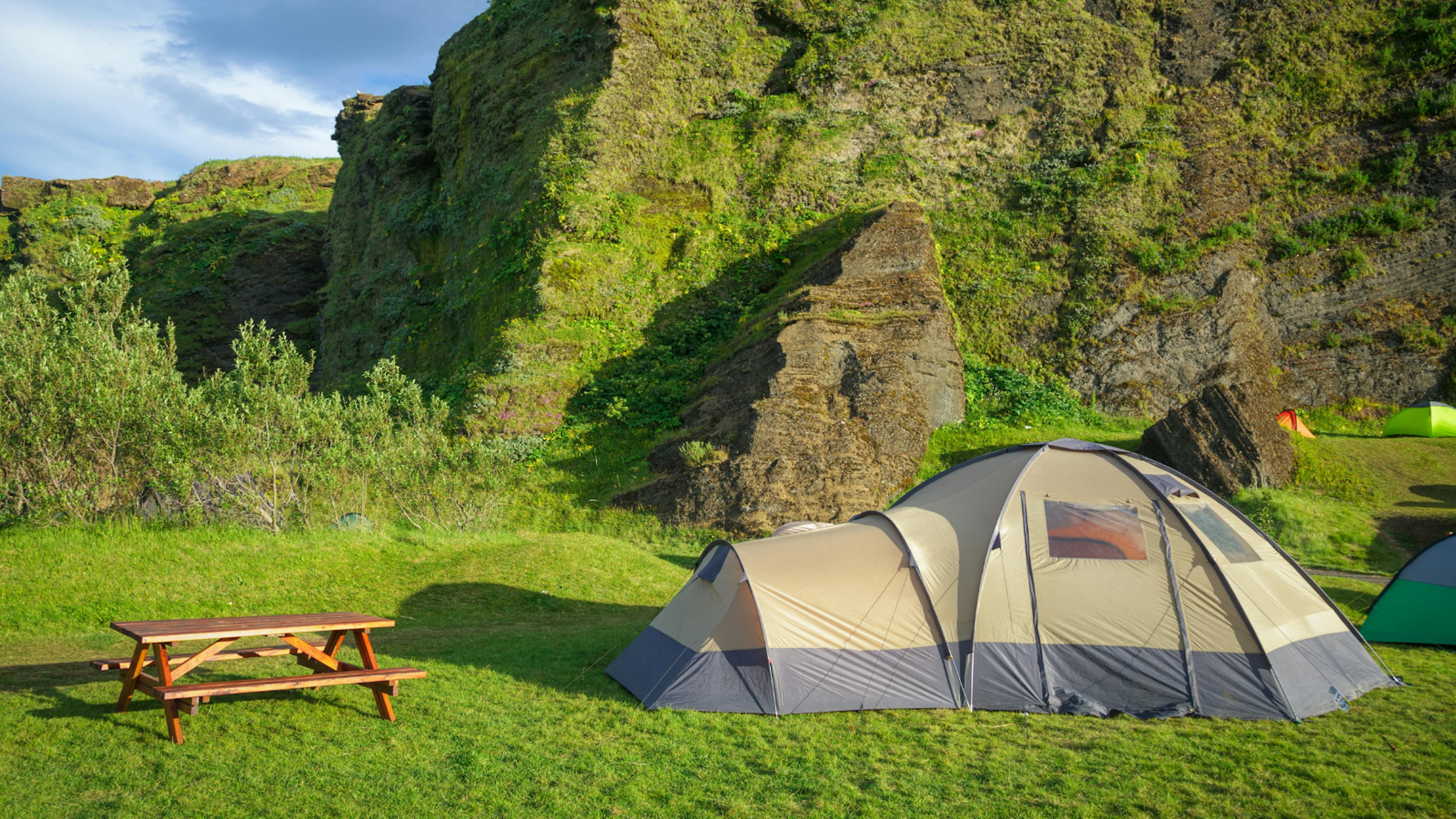 Dome tent next to picnic bench at campsite in Iceland.