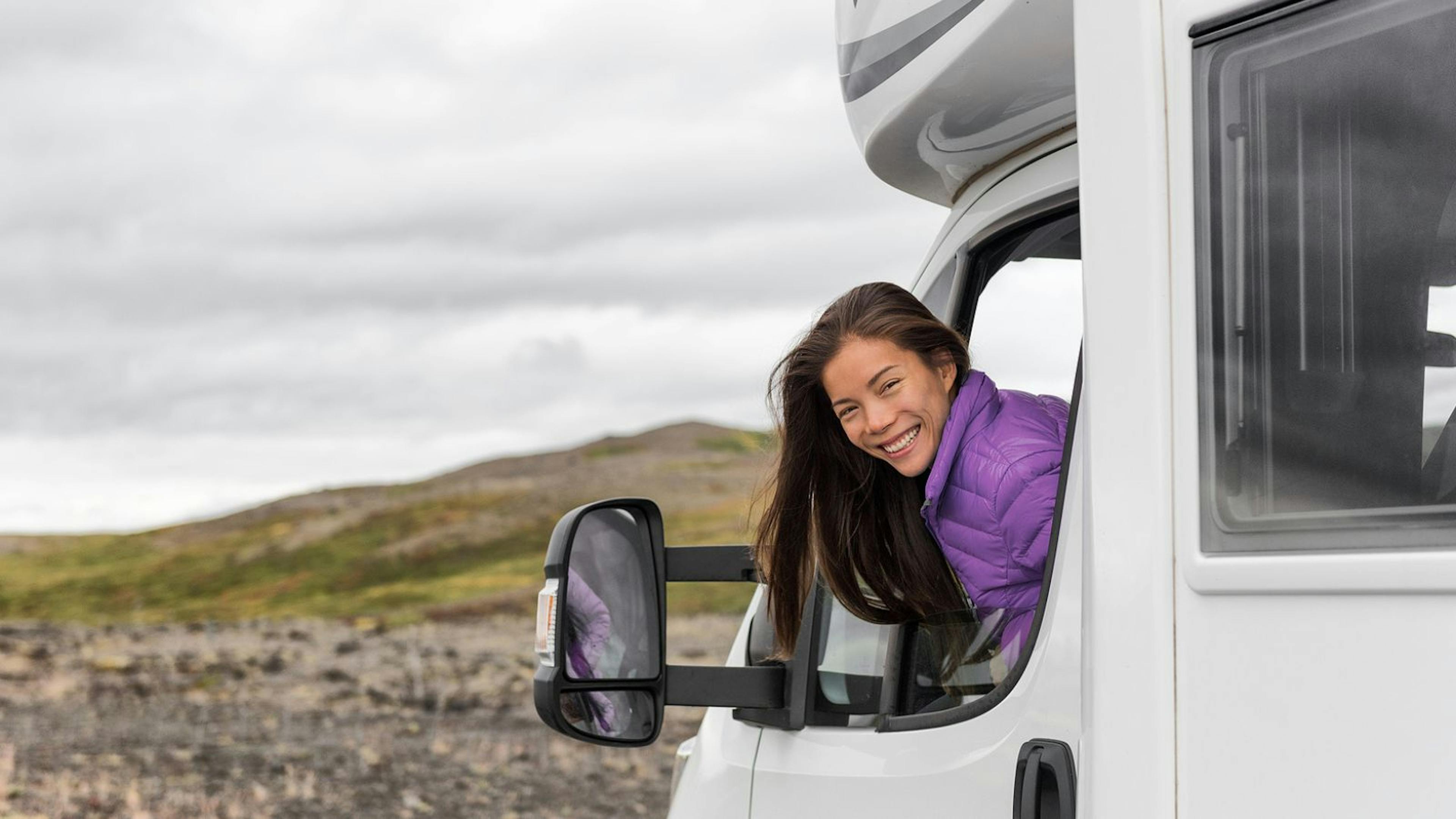 Woman looking out the window of a campervan and smiling in Iceland.