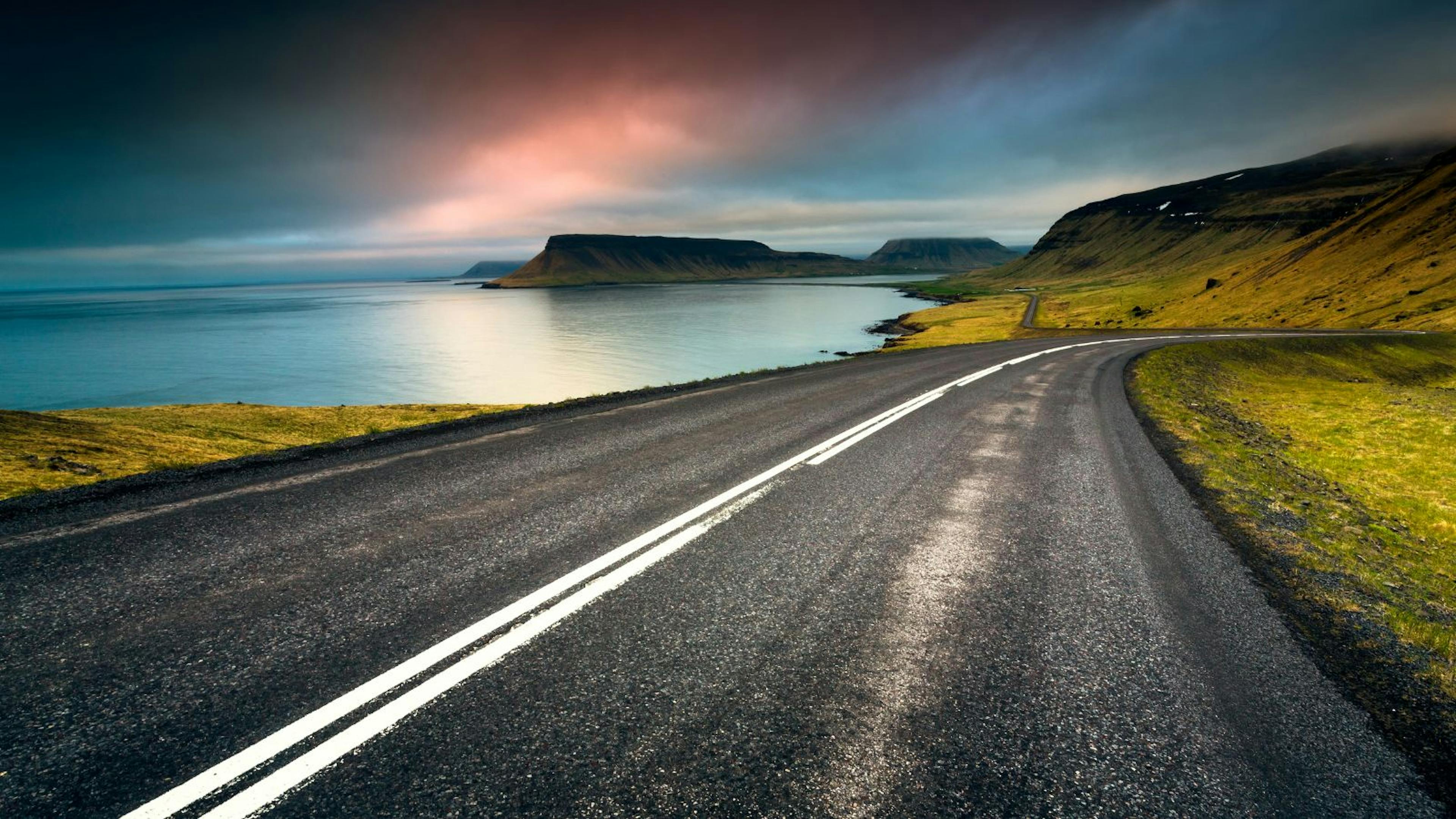 View of a road in Iceland running past a body of water.