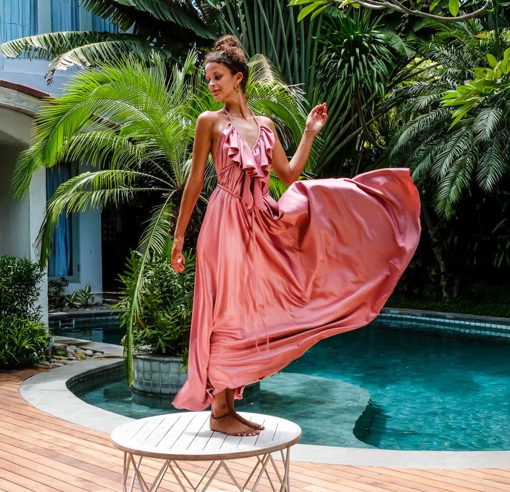 Woman wearing beautiful flowy dress standing by a pool