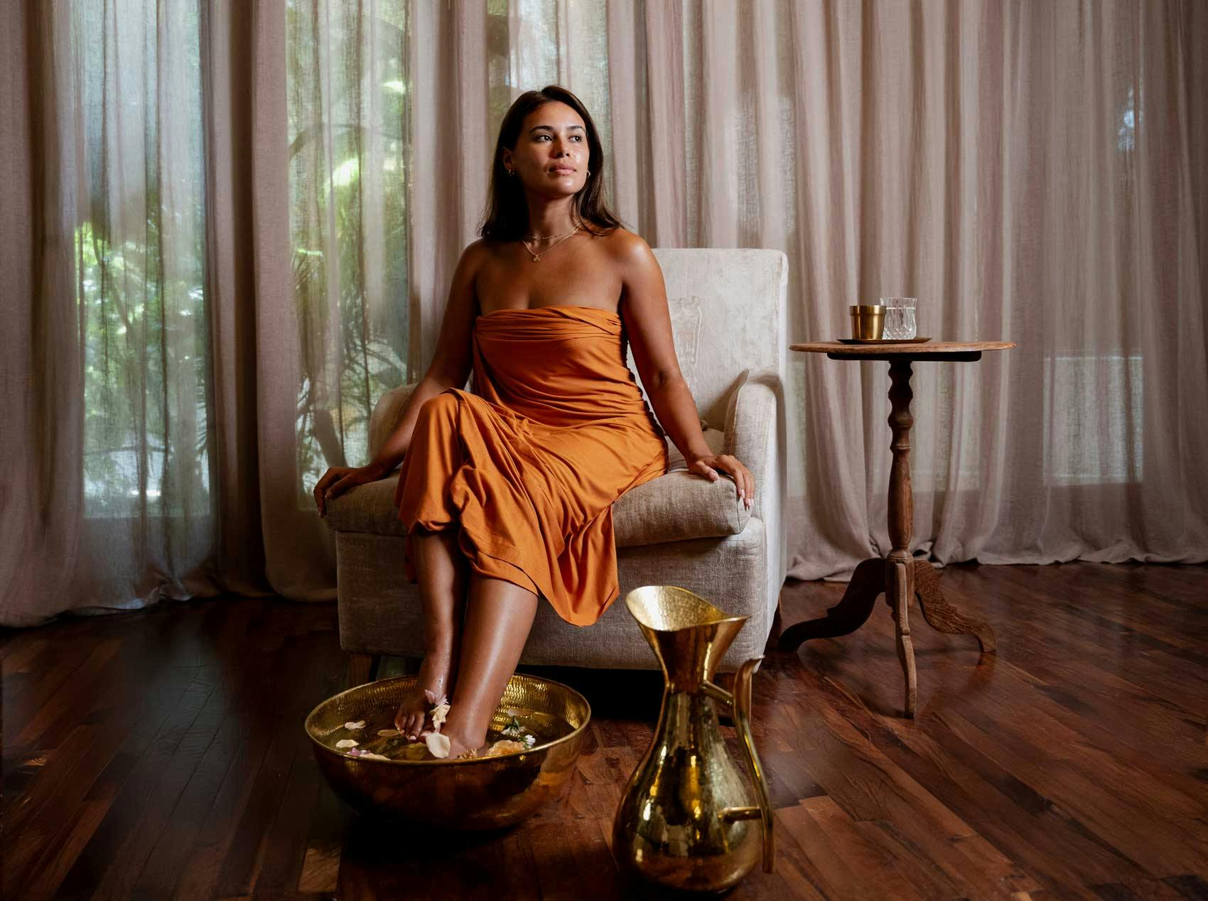 Woman in the signature sarong receiving a footbath in a gold bowl.