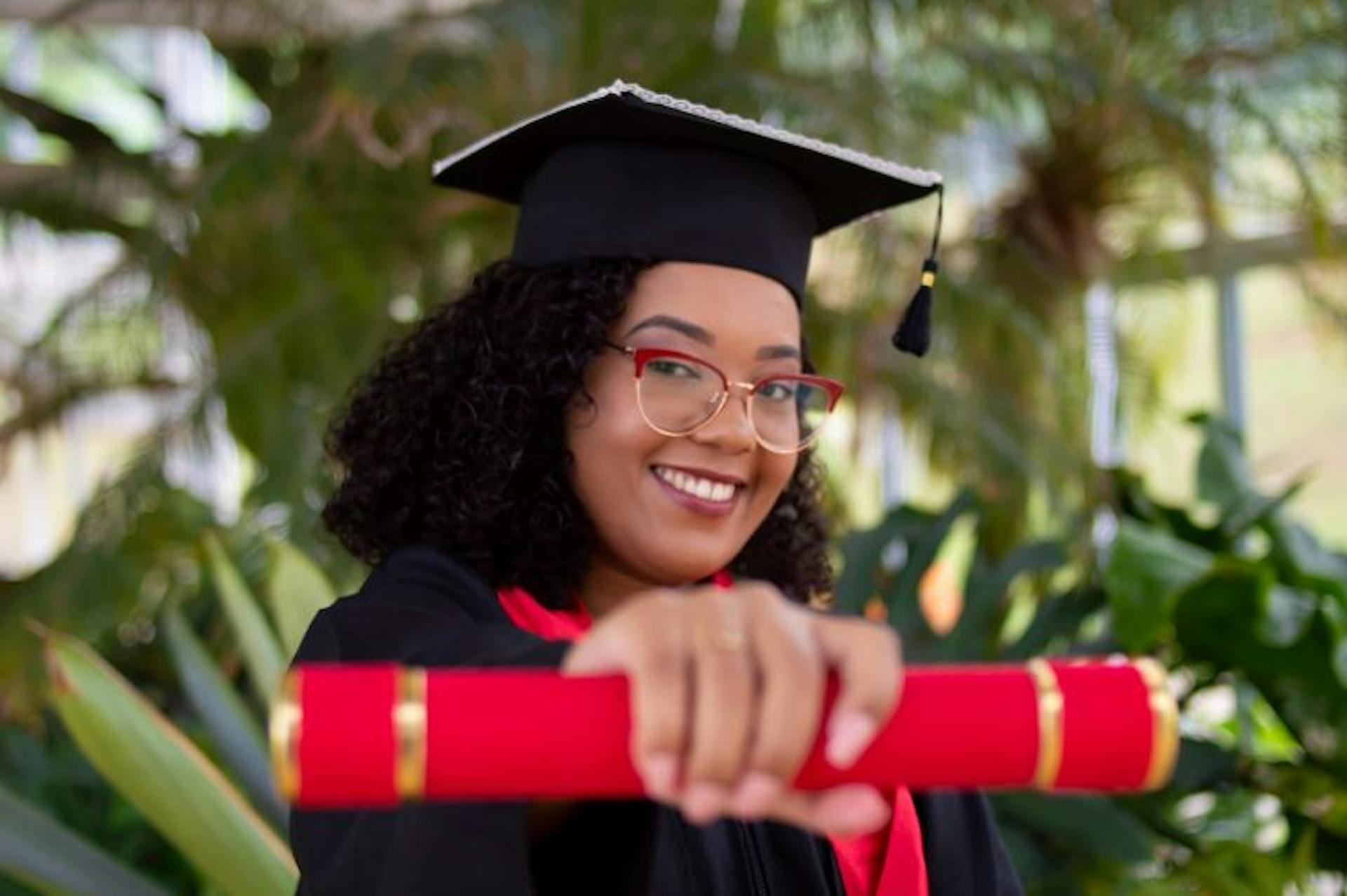 female student in cap and gown holding a red diploma
