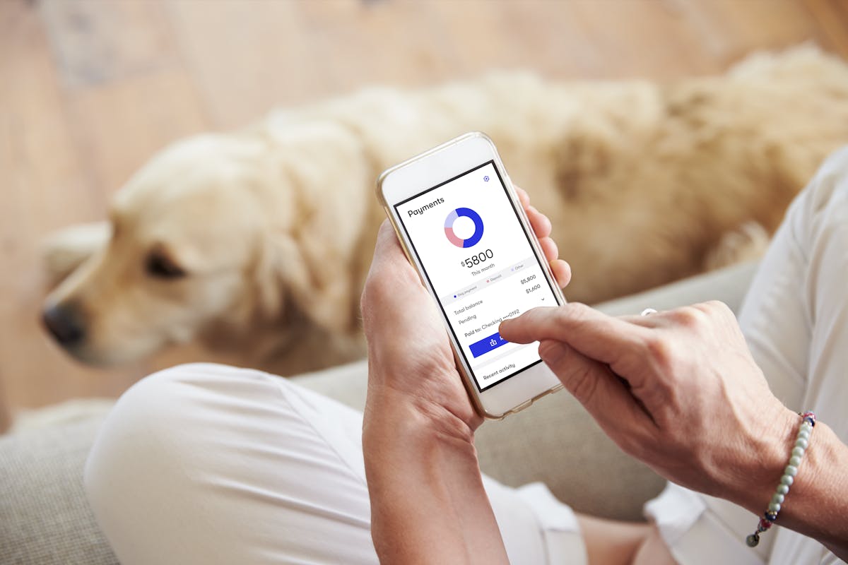 A woman holding a phone with Good Dog's payment view on the screen.