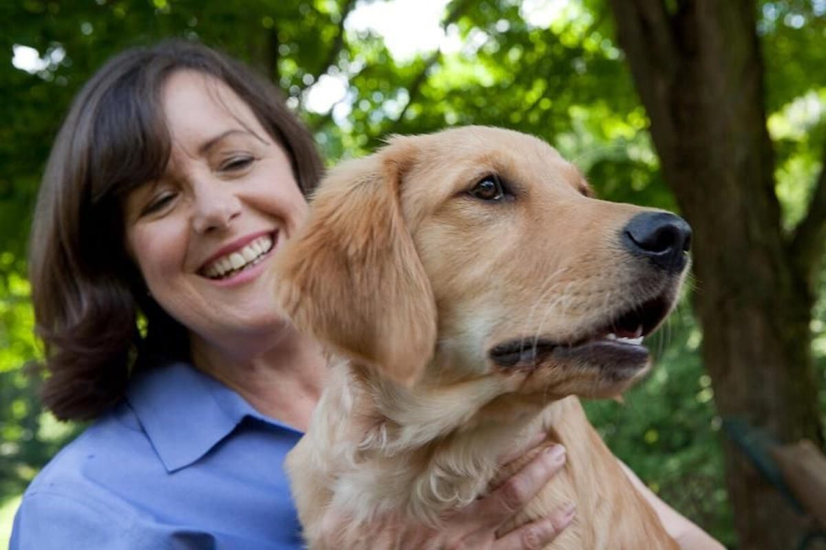 Gayle Watkins smiling with a golden retriever