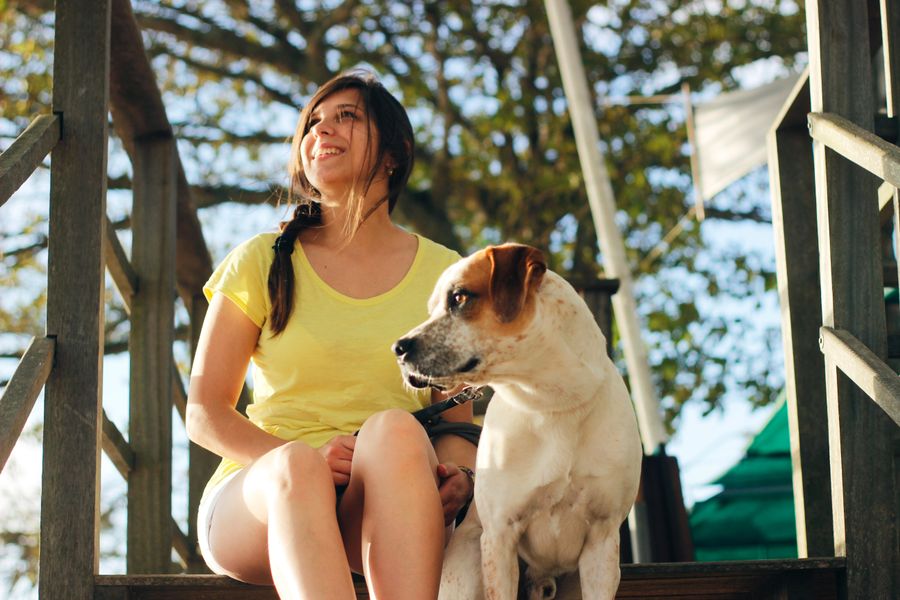 Smiling woman sitting with dog on porch, looking to the horizon together