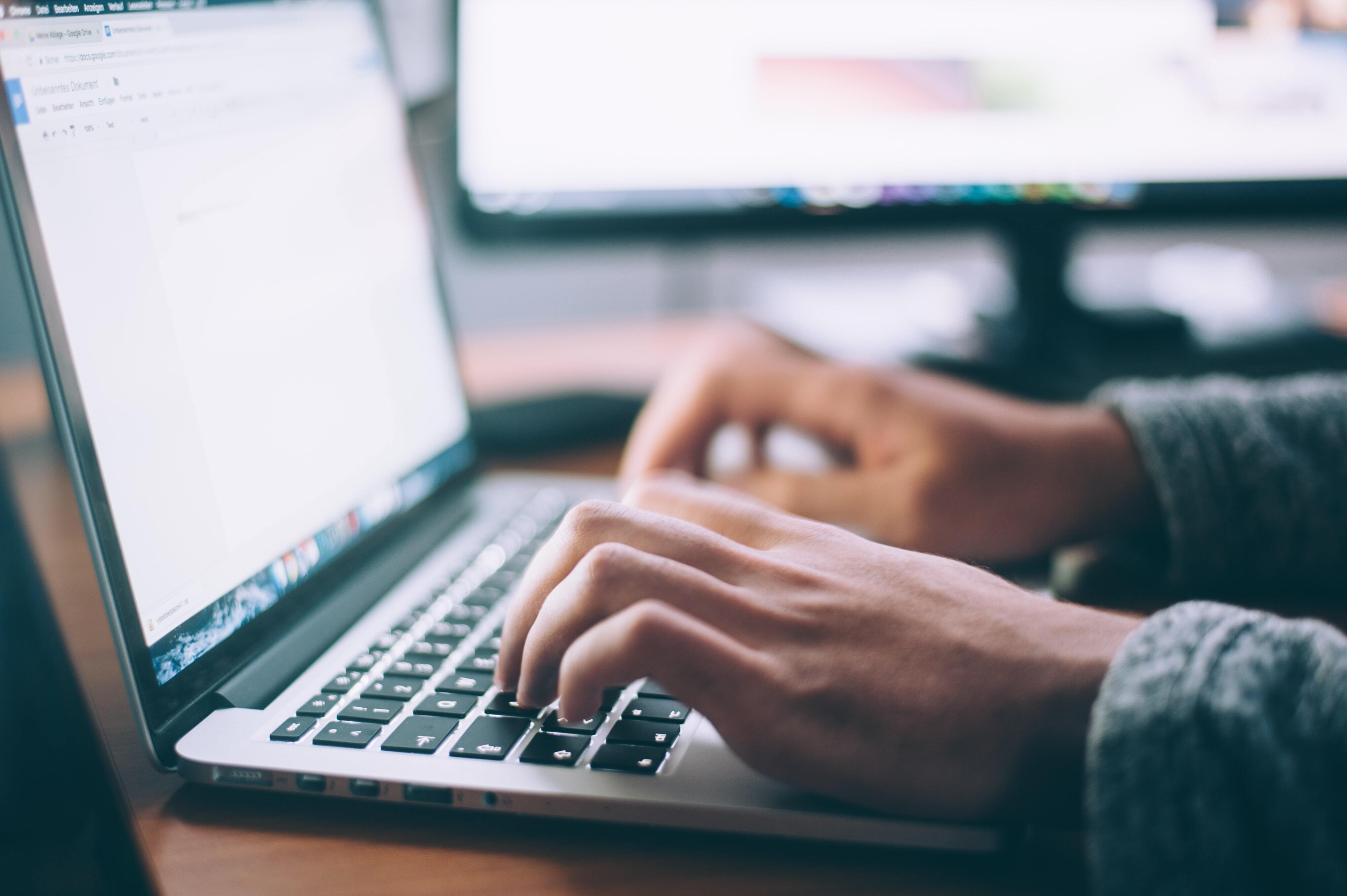 A closeup of a person typing on a laptop