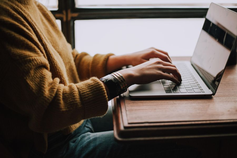 Person sitting at desk with laptop typing on keyboard