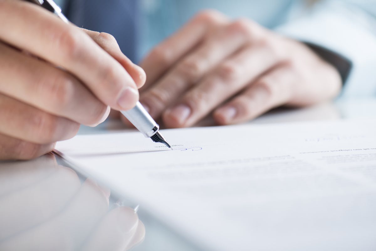 Close-up of a person signing a contract.