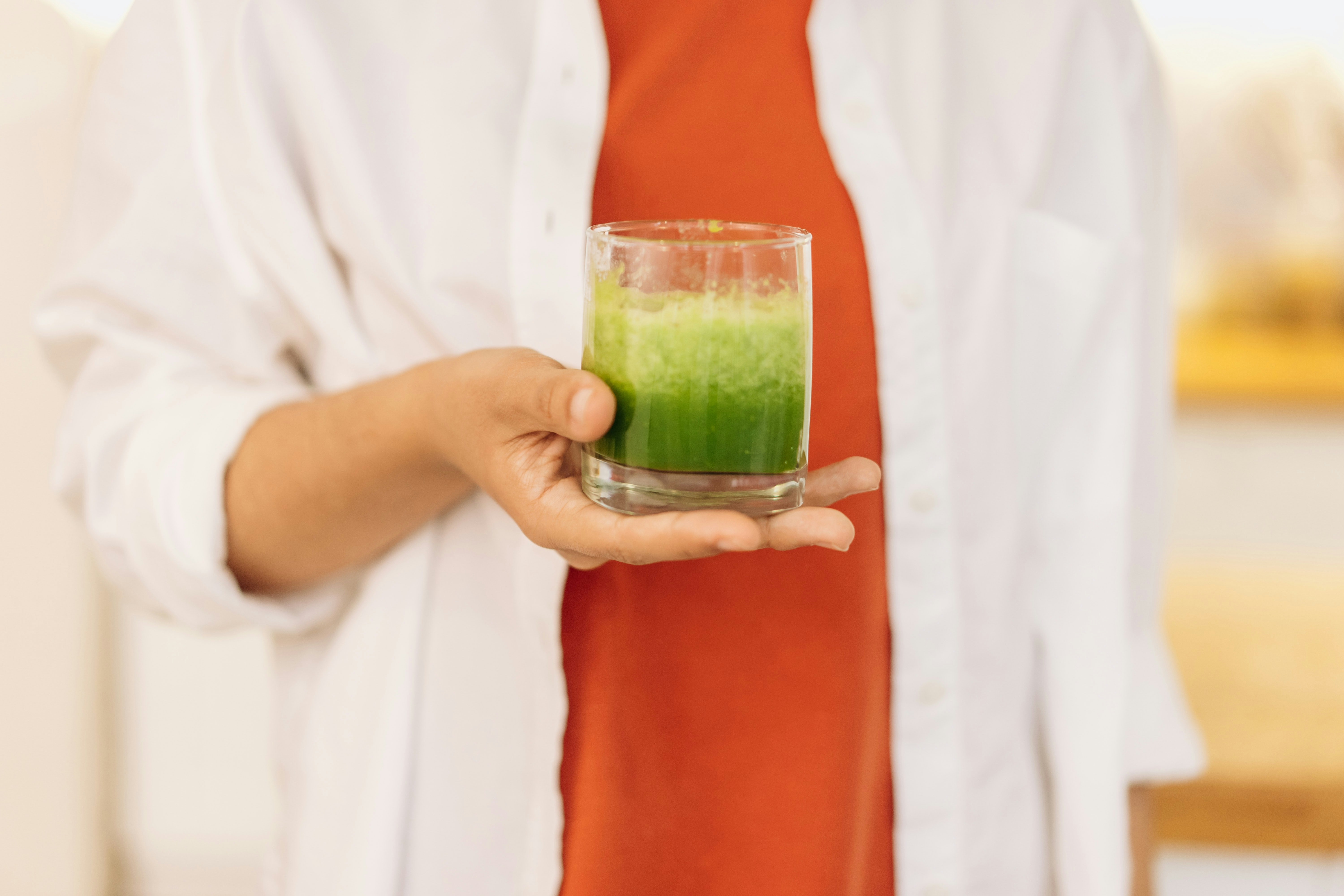 Person holding a glass of green juice. They know there's benefits to drinking green juice!