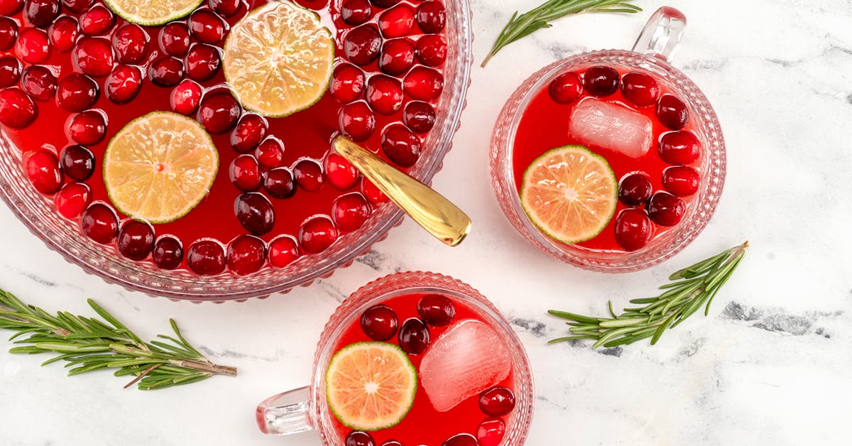 christmas punch in a punch bowl and glasses on a marble countertop