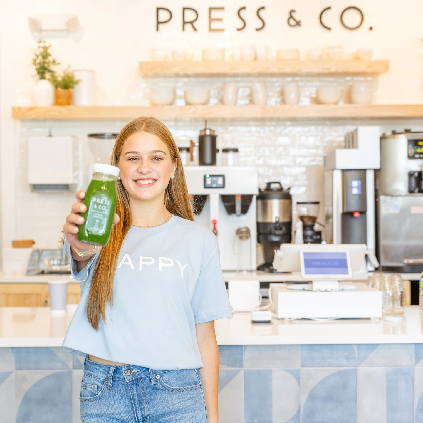A woman holding a bottle of green juice in a juice bar