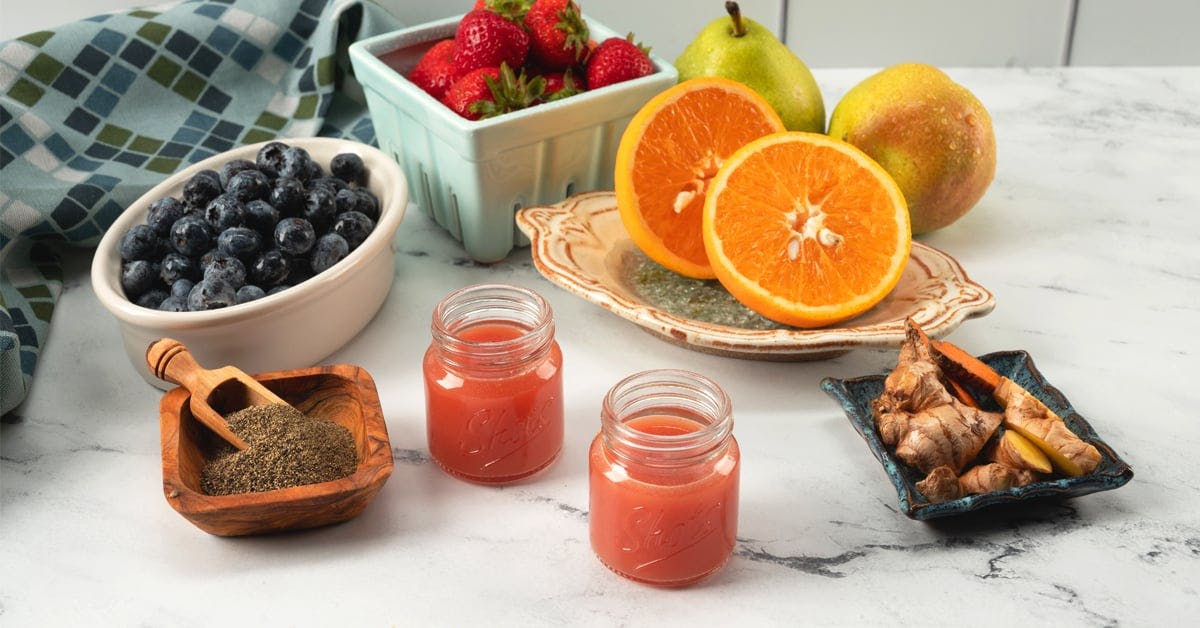 two ginger turmeric energy juice shots on a marble countertop