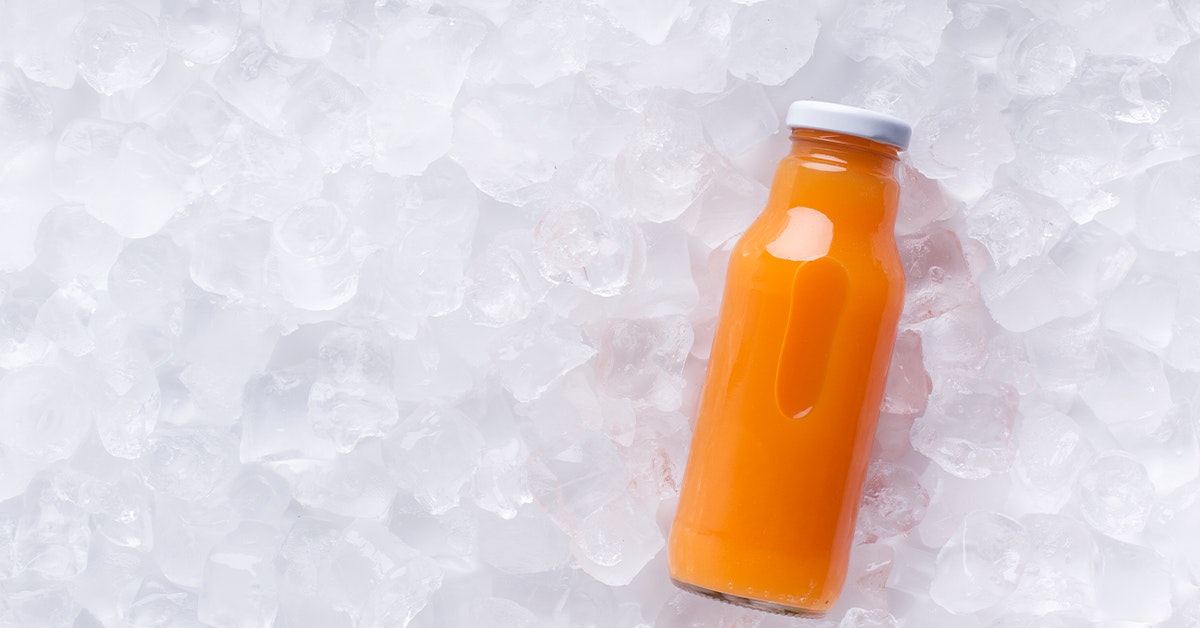 bottle of carrot juice sitting on ice
