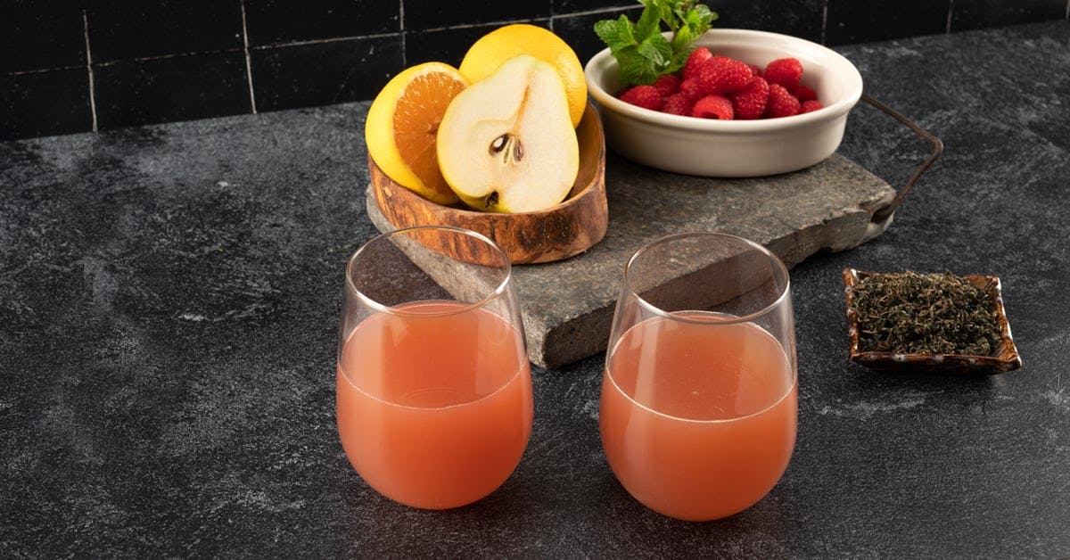 two glasses of jiaogulan tea juice on a black countertop