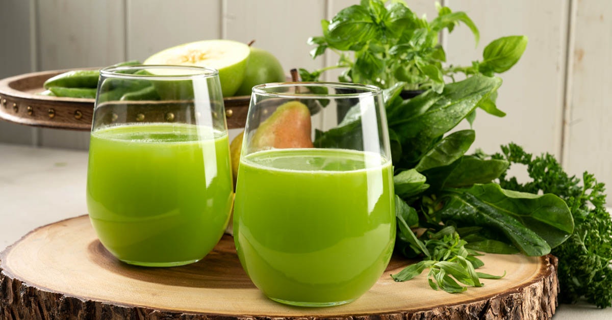 two glasses of holy basil tulsi herb green juice on a wooden platter