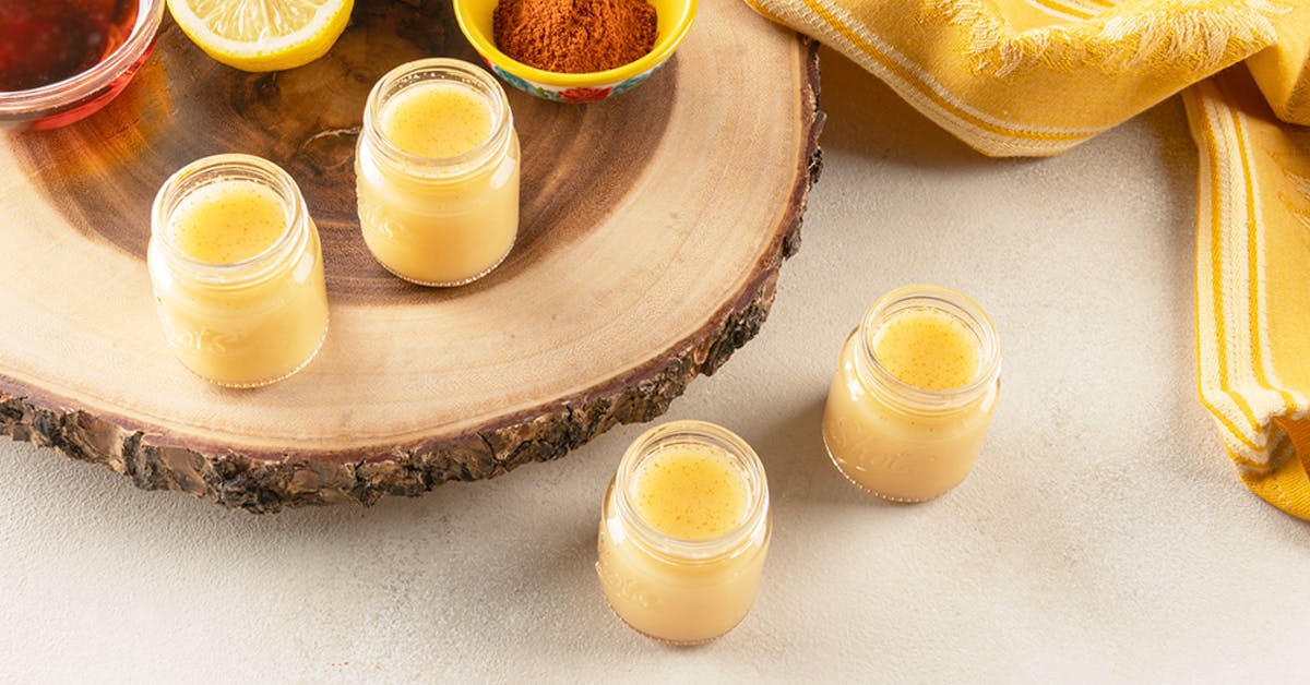 four ginger lemon cayenne juice shots on a wooden tray
