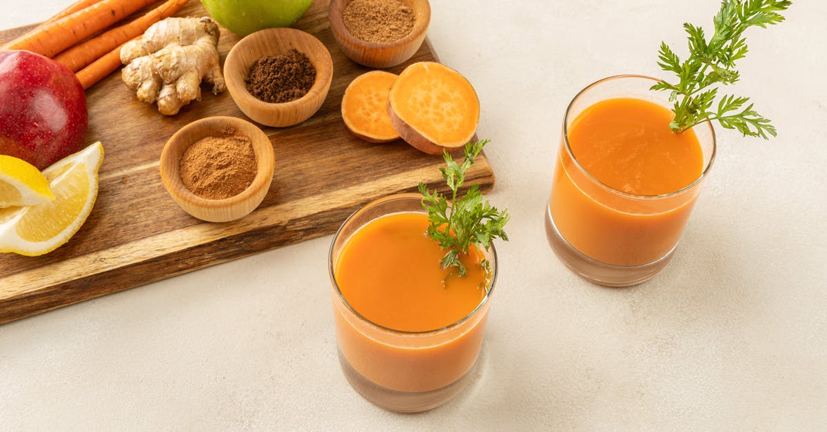 two glasses of sweet potato juice with ingredients on a cutting board
