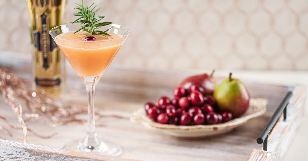 cranberry elderflower cocktail with orange and apple on a wooden serving tray