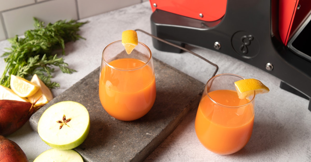 apple beet carrot abc juice next to a juicer on a table