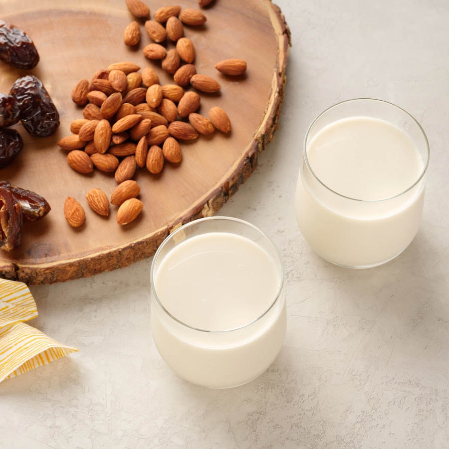 almond milk and ingredients to make this cold pressed recipe including dates, vanilla bean and raw almonds
