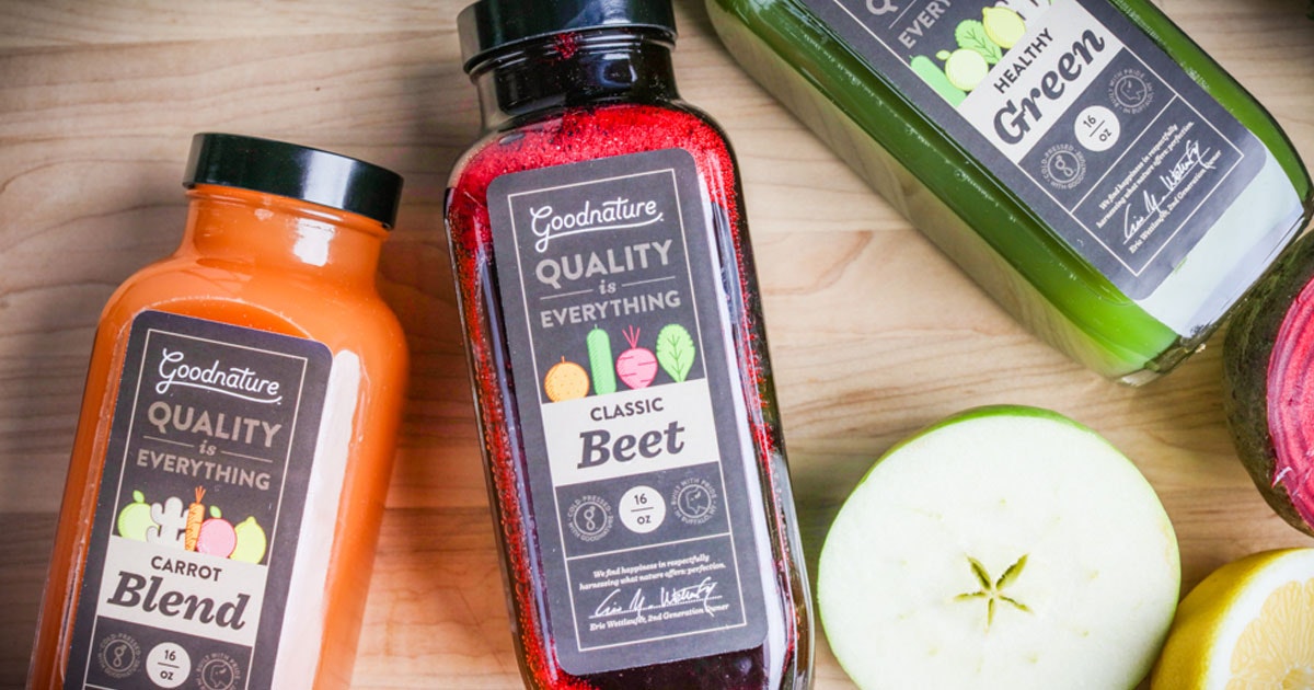 bottles of beet juice, green juice and carrot juice on a wooden table