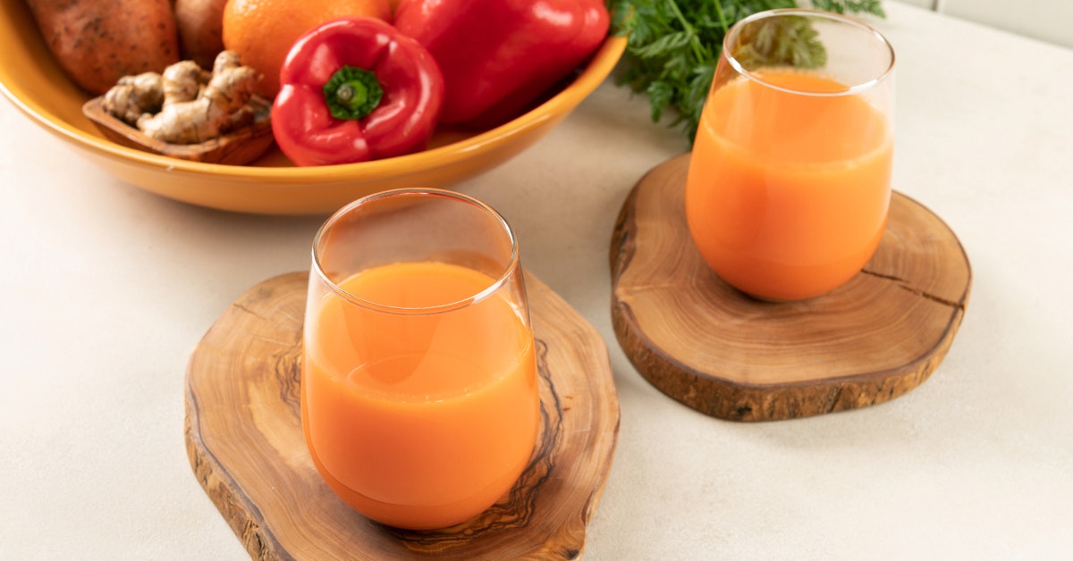 red bell pepper juice on a white table next to a bowl of ingredients