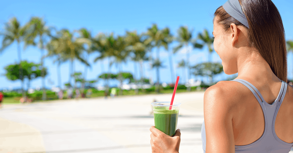 woman near the beach on a juice fast with a glass of green juice