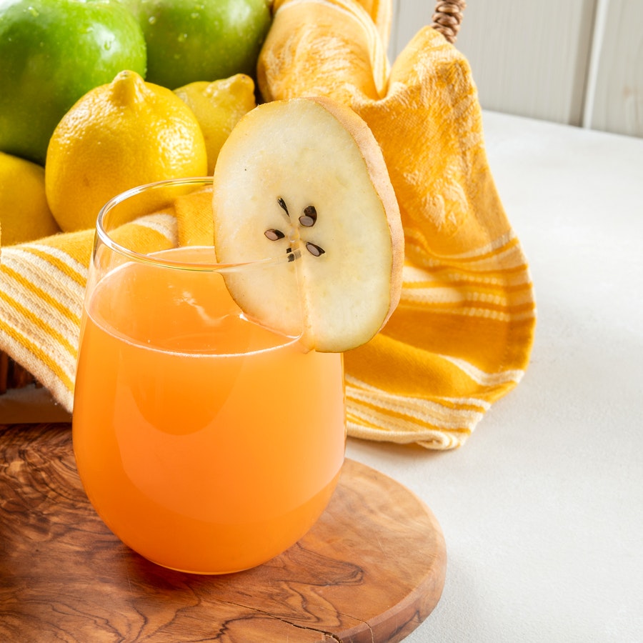 glass of apple, carrot, pear cold pressed juice on a wooden cutting board